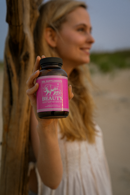 Woman holding a bottle labeled 'Beauty' against a natural background
